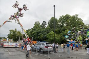 Police surveillance vehicle with elevated camera monitoring a crowded fairground.