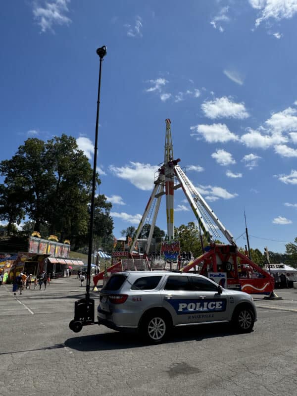 Knoxville Police Department vehicle with RATT RQ610 mobile surveillance tower deployed at a special event in front of an amusement park ride