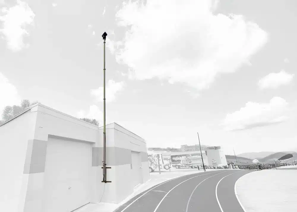 Grayscale image of wall-mounted pneumatic telescopic mast installed for facility surveillance.