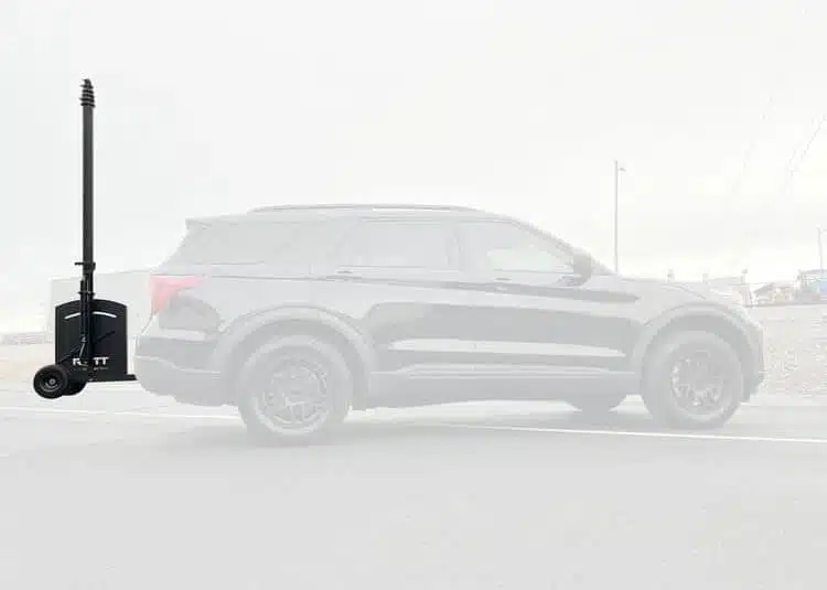RATT hitch-mounted telescopic mast deployed on an SUV in an urban environment; grayscale image.