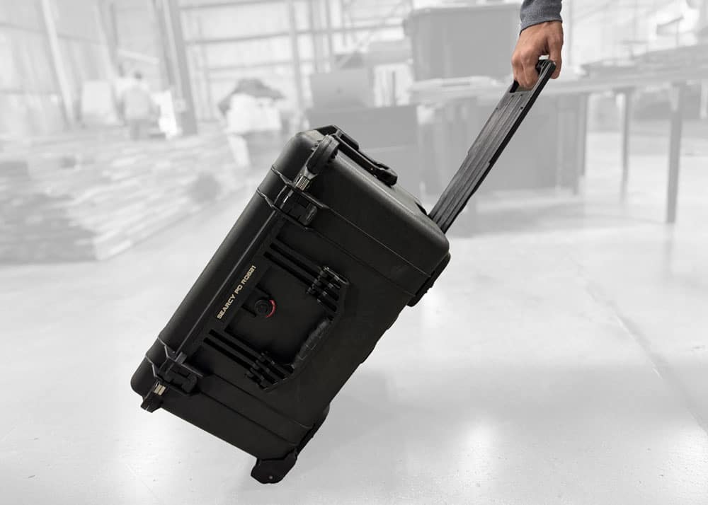Man pulling a rugged Pelican hard case with wheels in warehouse