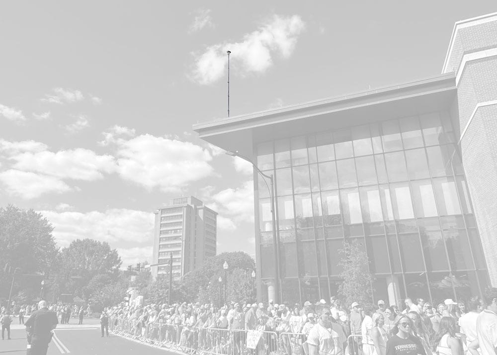 Tripod-mounted telescopic mast with PTZ camera on building rooftop for event surveillance