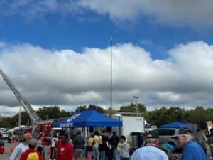 Crowds gather around emergency response vehicles, an elevated communications mast, and agency tents at The University of Alabama’s High School Job Fair.